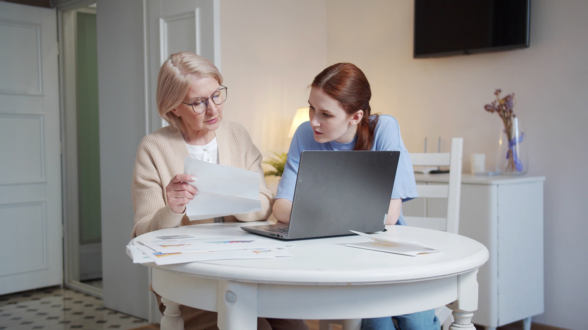 two women sitting at computer with documents